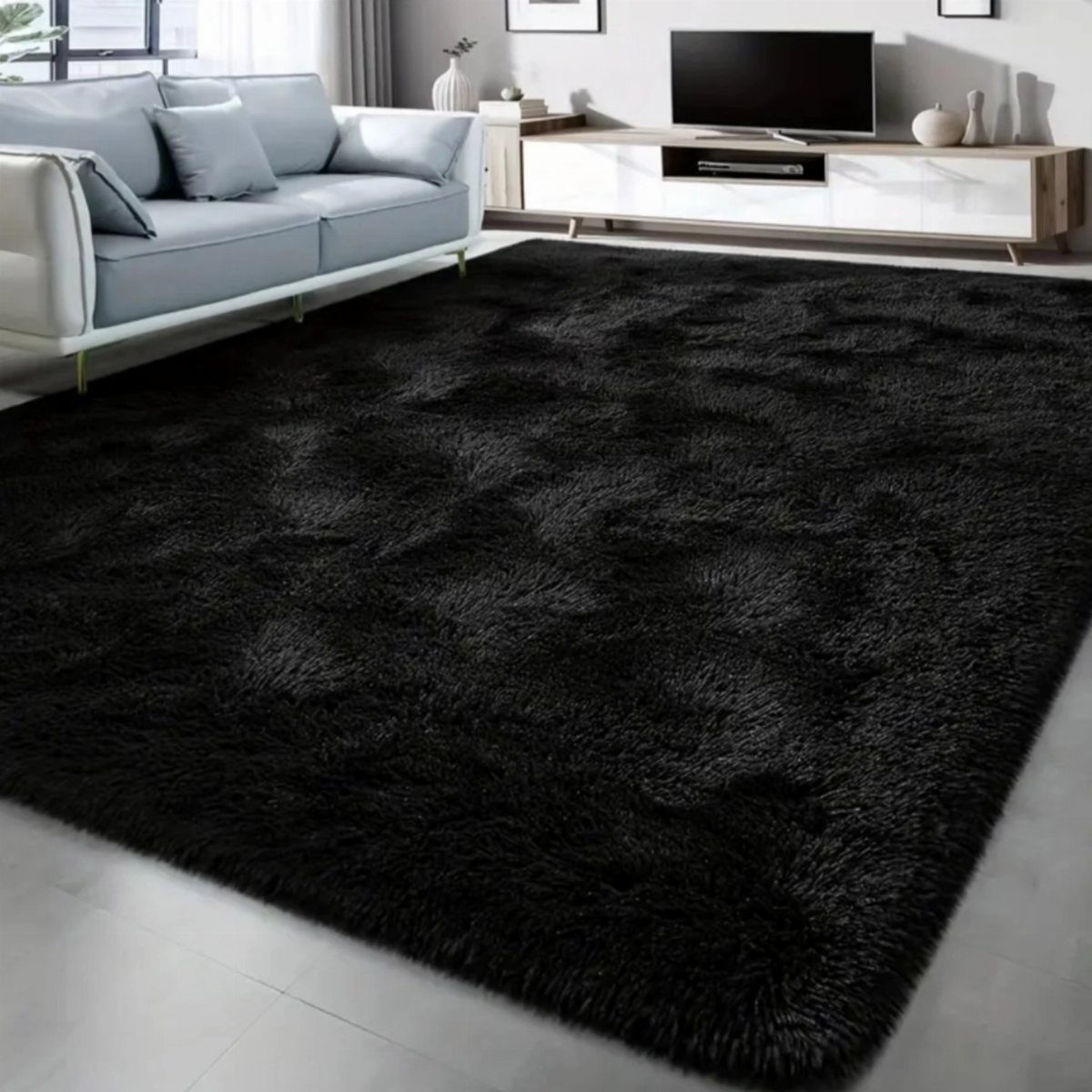 Black shag rug in a living room with a light grey sofa.