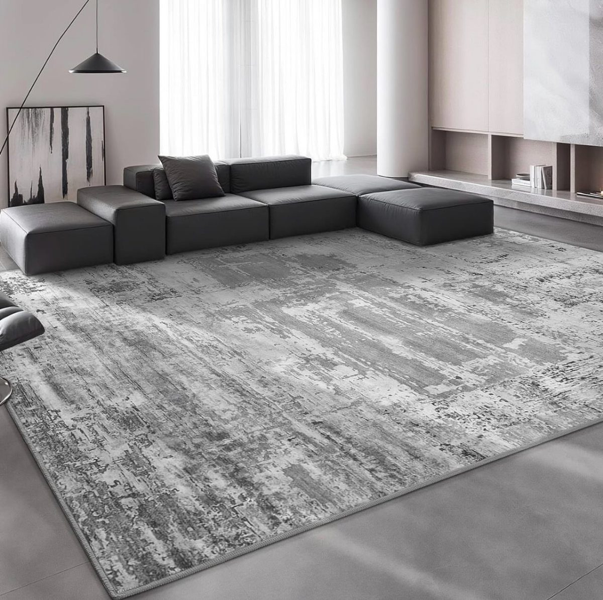 Grey and white distressed area rug under a dark grey modular sectional sofa.