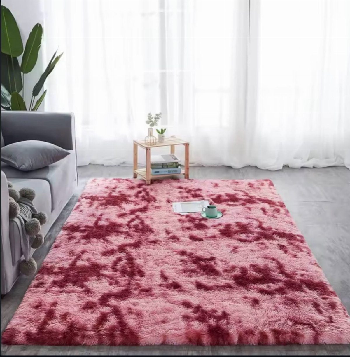 Pink and magenta marbled shag rug in a living room with grey sofa.