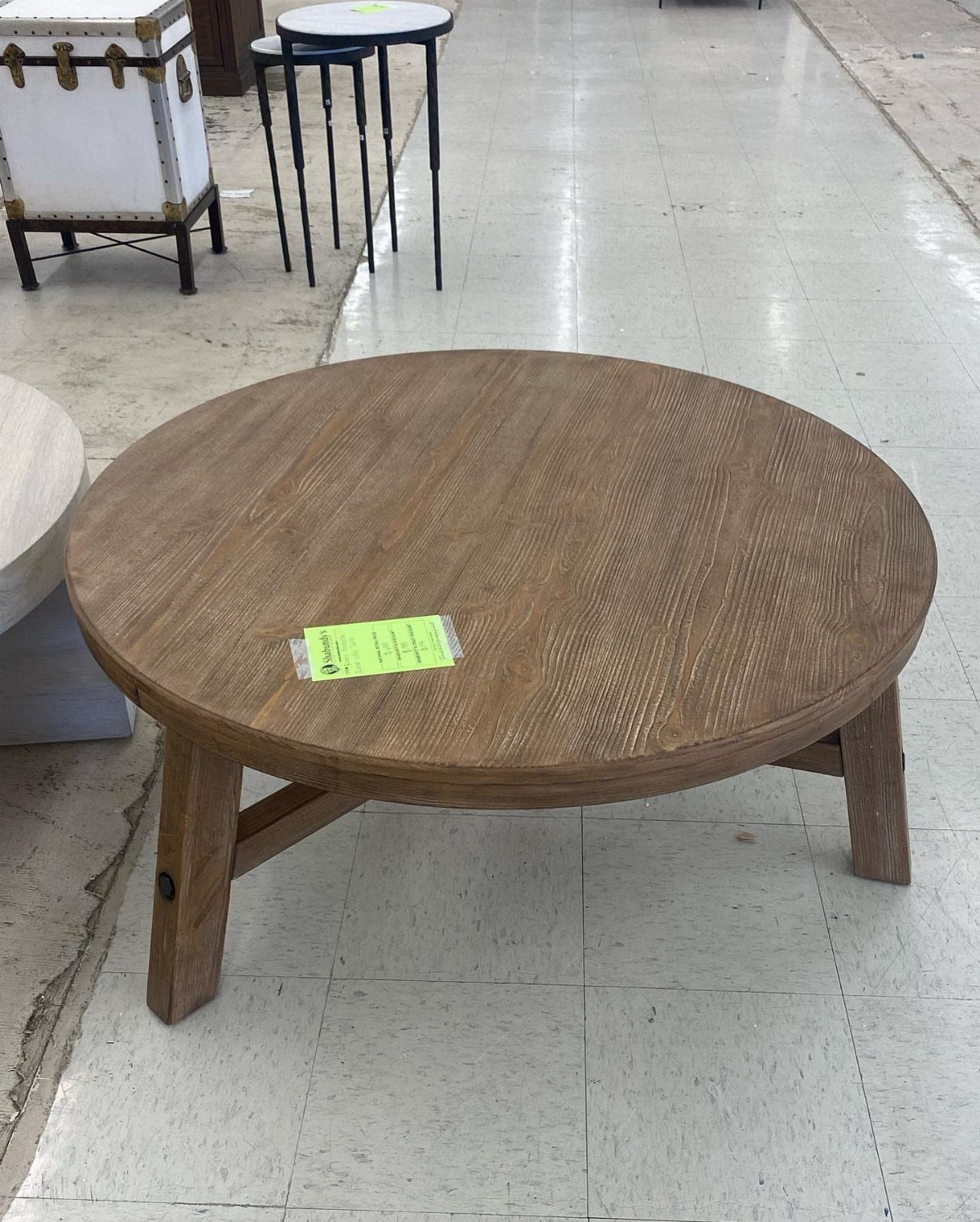 Round rustic wooden coffee table with natural brown finish on a tiled floor