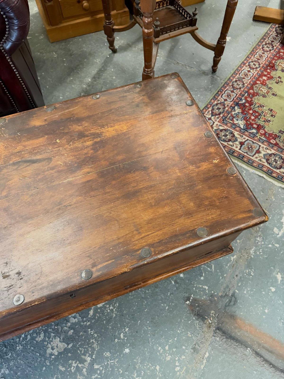 Rustic wooden chest coffee table with metal studs on a concrete floor