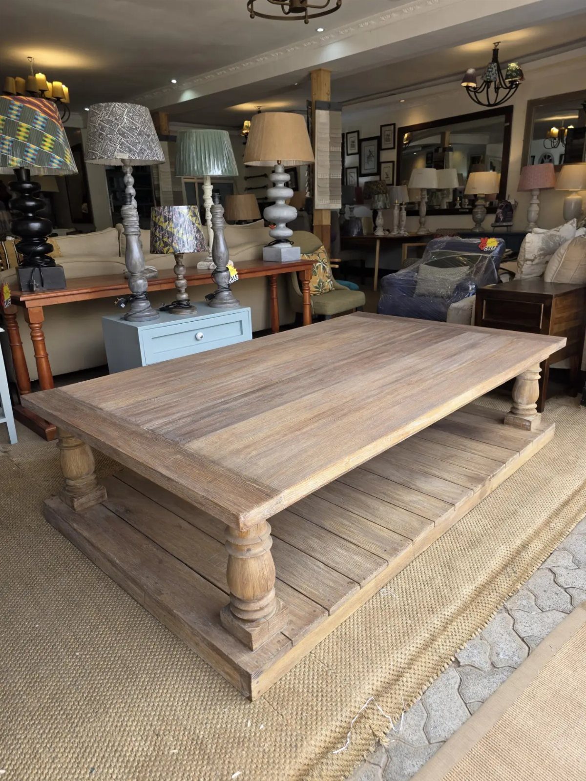 Light-colored weathered wooden coffee table with two tiers on a jute rug