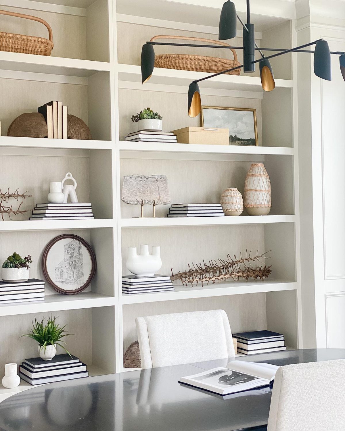 White built-in shelves with decor against a soft grey wall in an office.