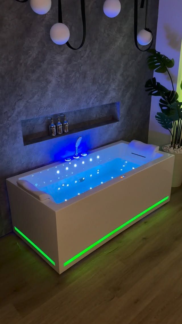 Modern white bathtub with blue interior and green exterior LED lighting in bathroom