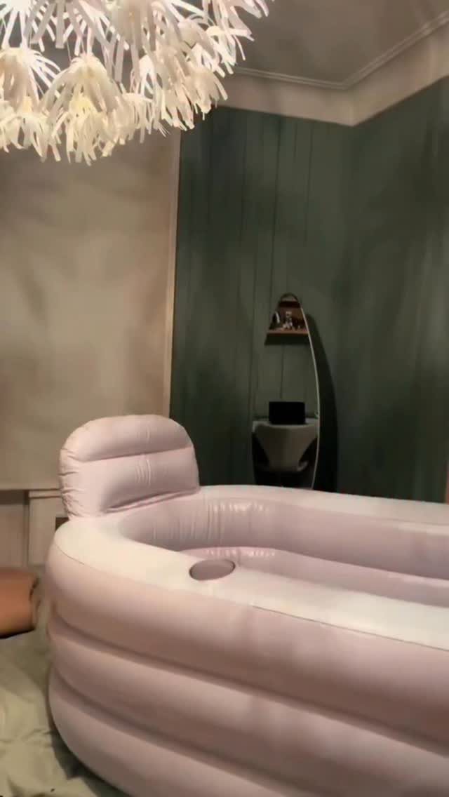 Inflatable white spa tub in a room with a green wall and chandelier.