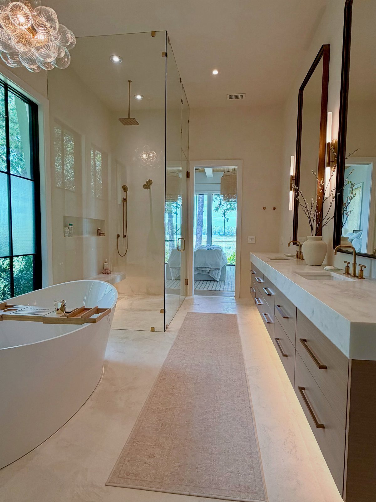 White freestanding bathtub in a bright bathroom with large windows and natural light.