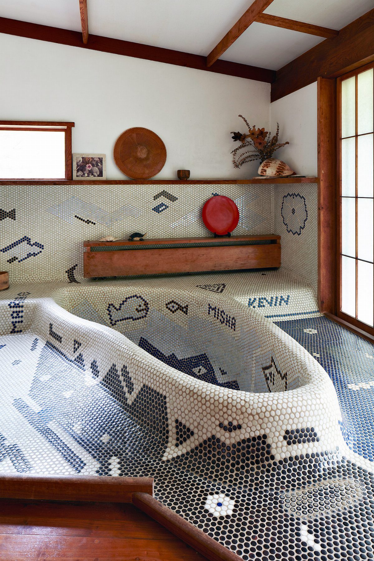 Sunken bathtub surrounded by blue and white mosaic tiles with decorative patterns.
