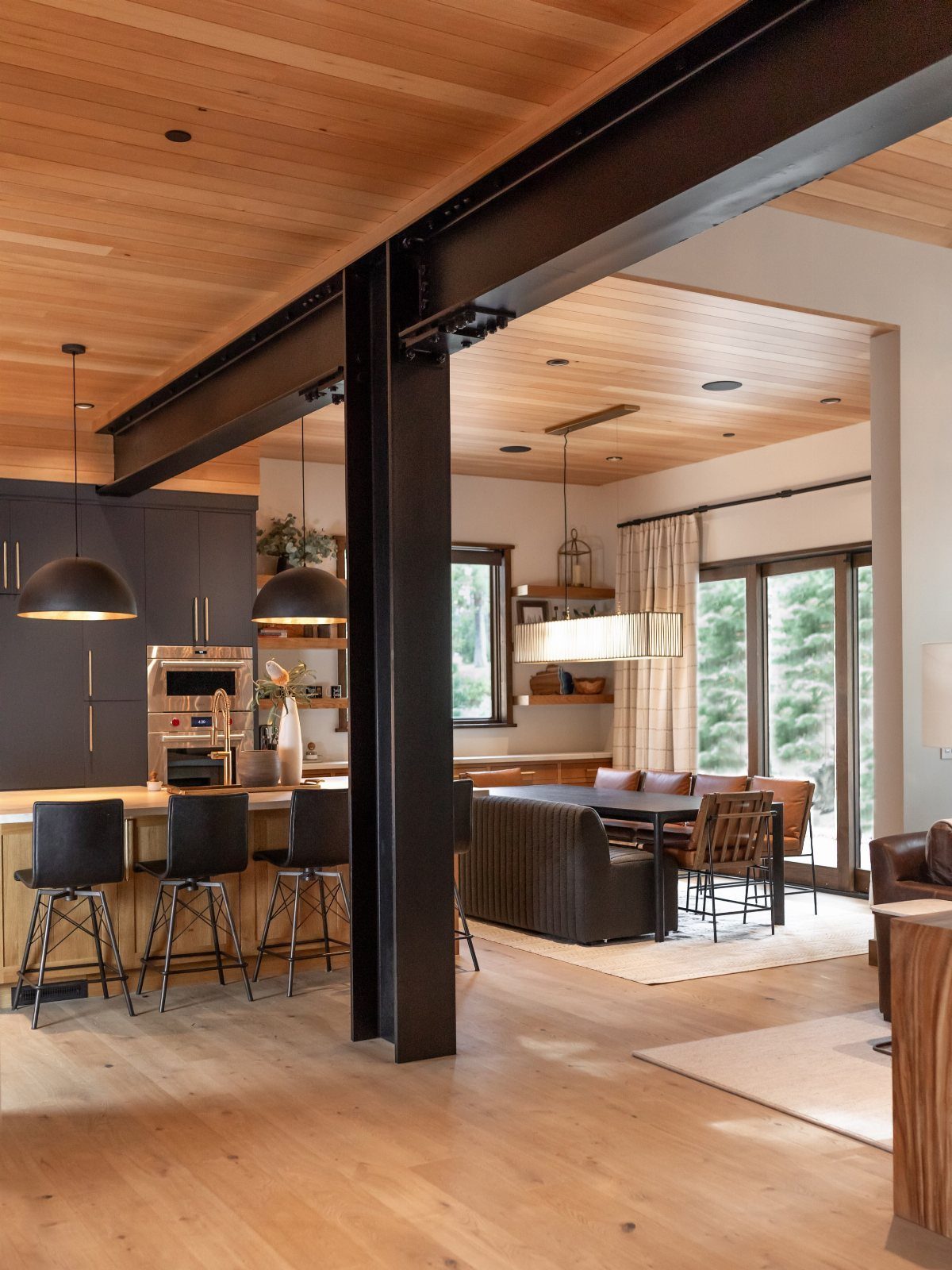 Modern interior with black steel beams, light wood ceilings, and open living space.