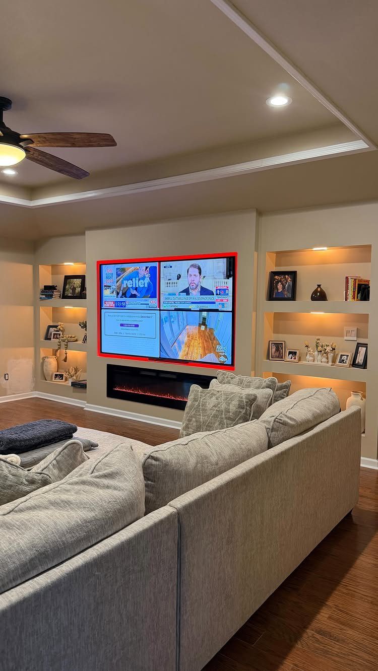 Recessed television screen above a modern electric fireplace in a beige living room
