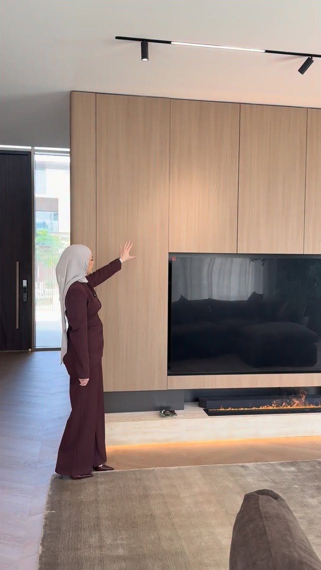 Light wood flat-panel wall with a recessed television and linear fireplace below.