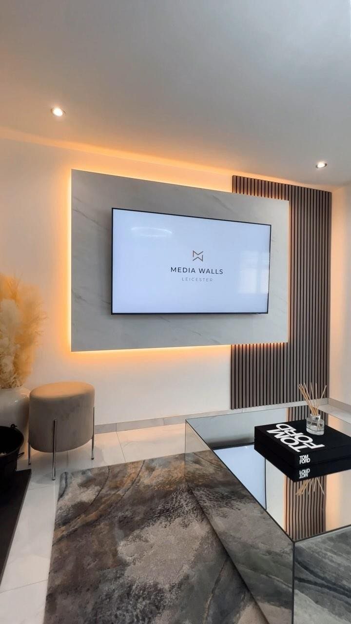 Flat-screen TV on a backlit marble panel next to vertical wood slat walling.