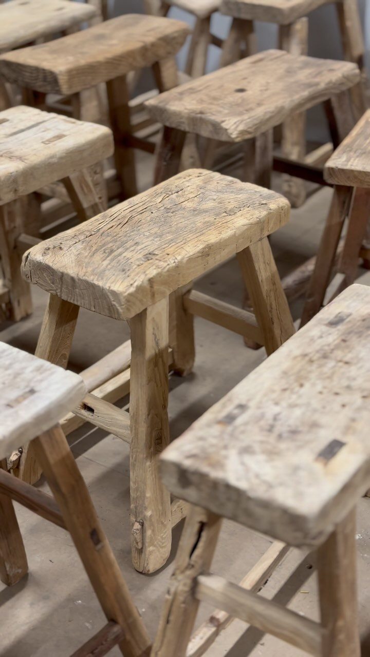 Rustic wooden stools with distressed surfaces arranged in a group on a floor.