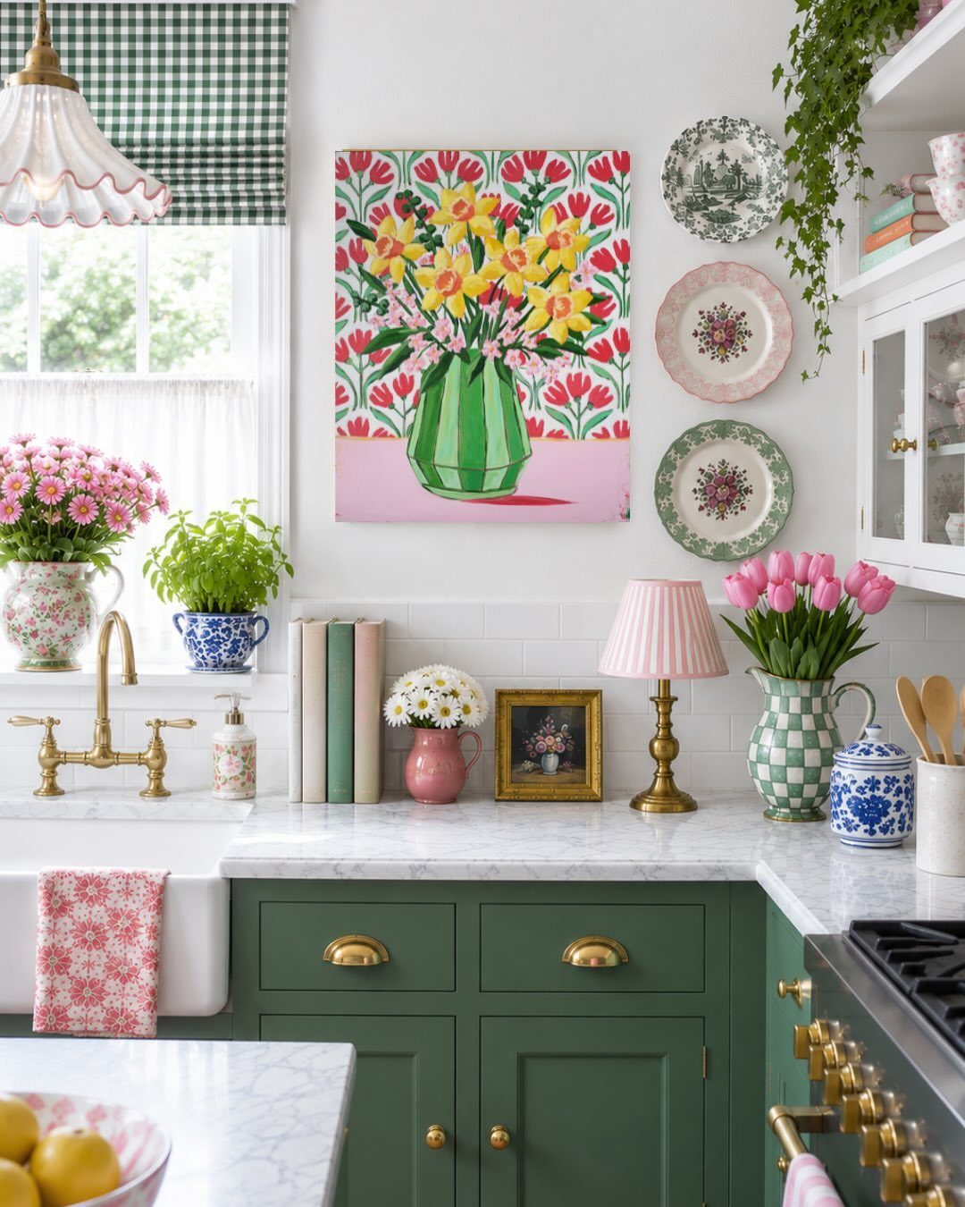 Colorful floral painting hanging on a white wall above green kitchen cabinets.