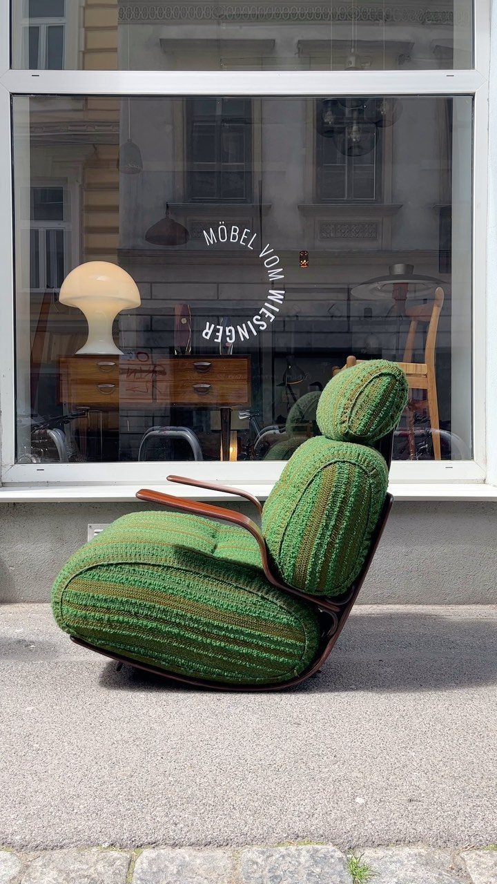 Green textured mid-century modern lounge chair sitting on a sidewalk outside a furniture store.