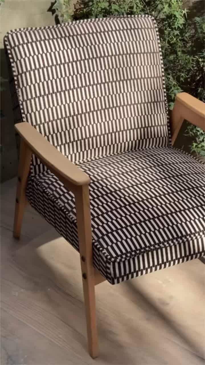Mid-century modern armchair with black and white geometric upholstery and light wood frame.