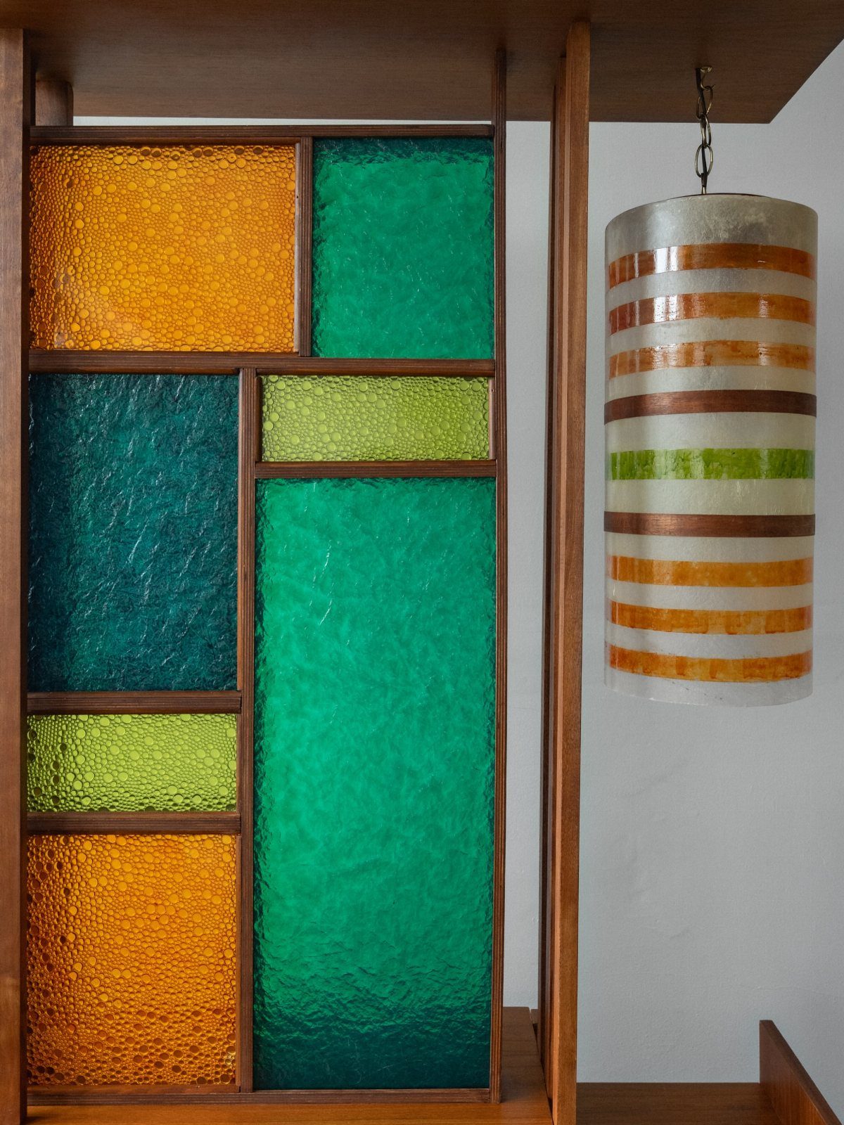 Wooden furniture with colorful textured glass panels and a matching striped cylindrical lamp.
