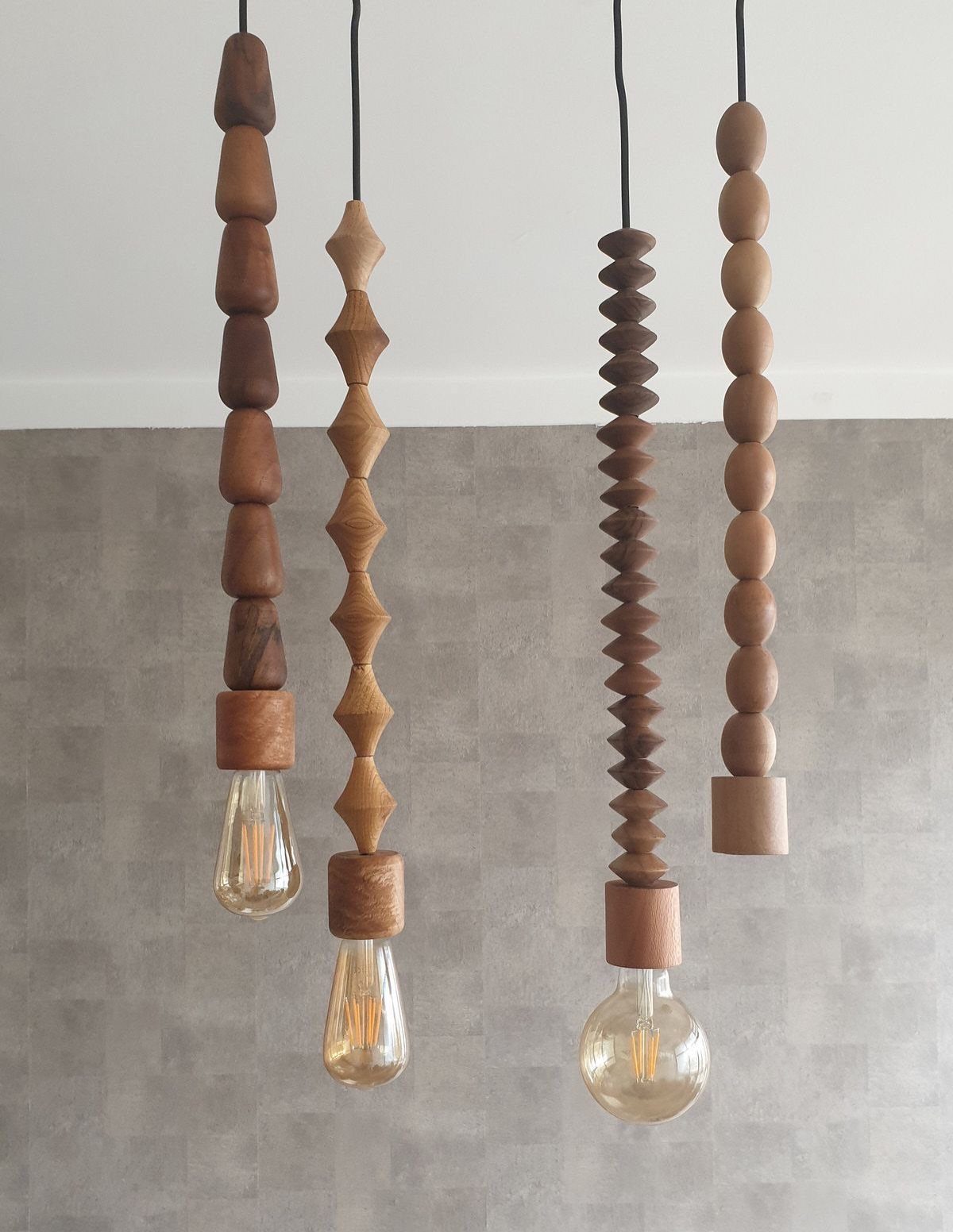 Wooden beaded pendant lights with glowing bulbs against a grey textured wall