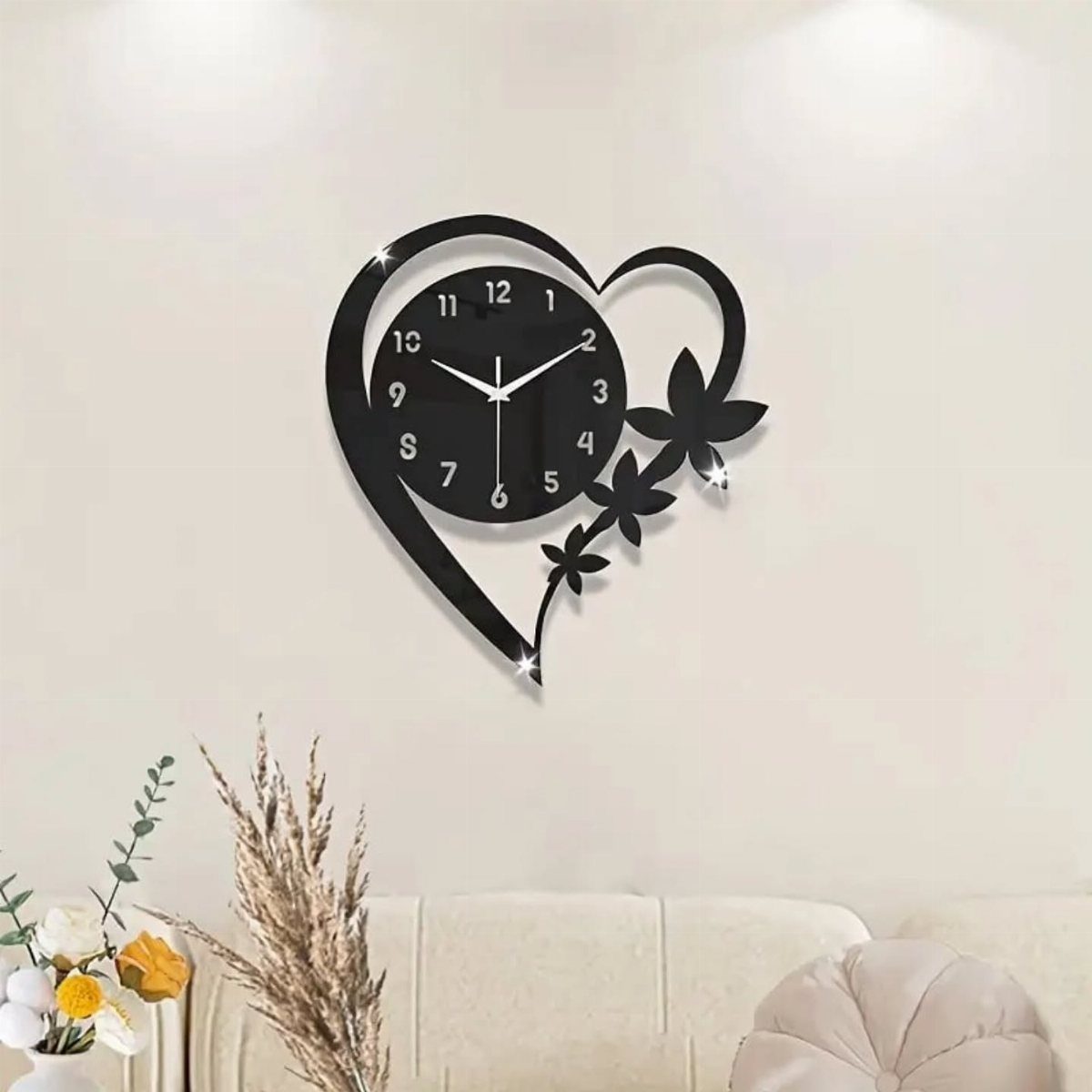 Heart-shaped black wall clock hanging on a white wall above a cream couch