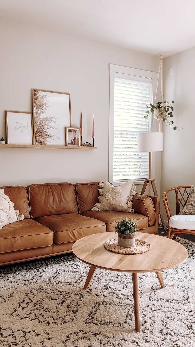 Brown leather couch with framed wall art on a shelf above it.