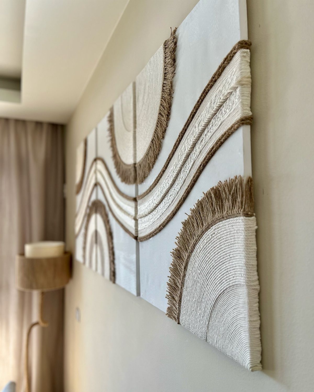 Textured fiber art with white and brown yarn curves on white canvas panels.