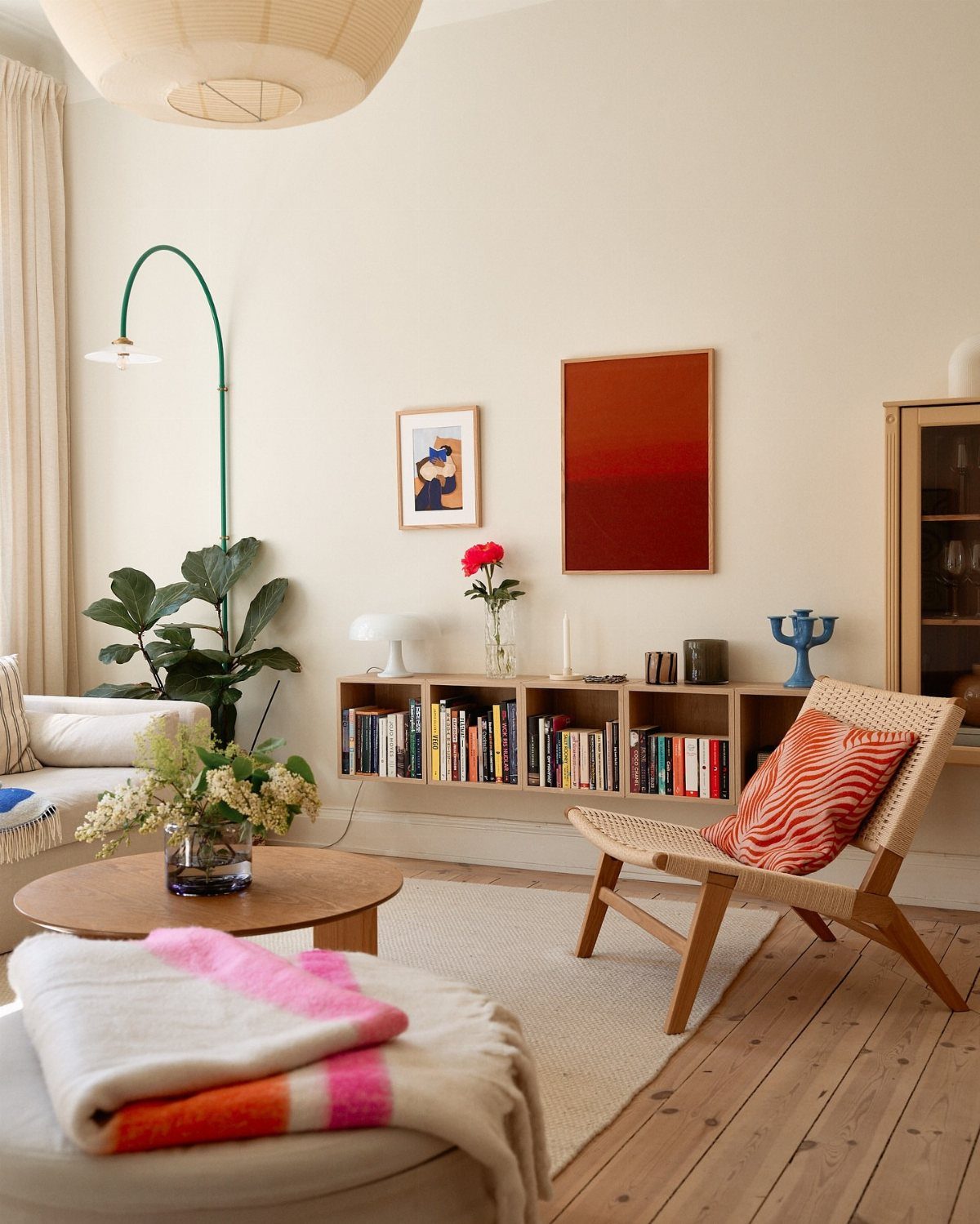 Bright living room with neutral tones accented by red artwork and a patterned pillow.