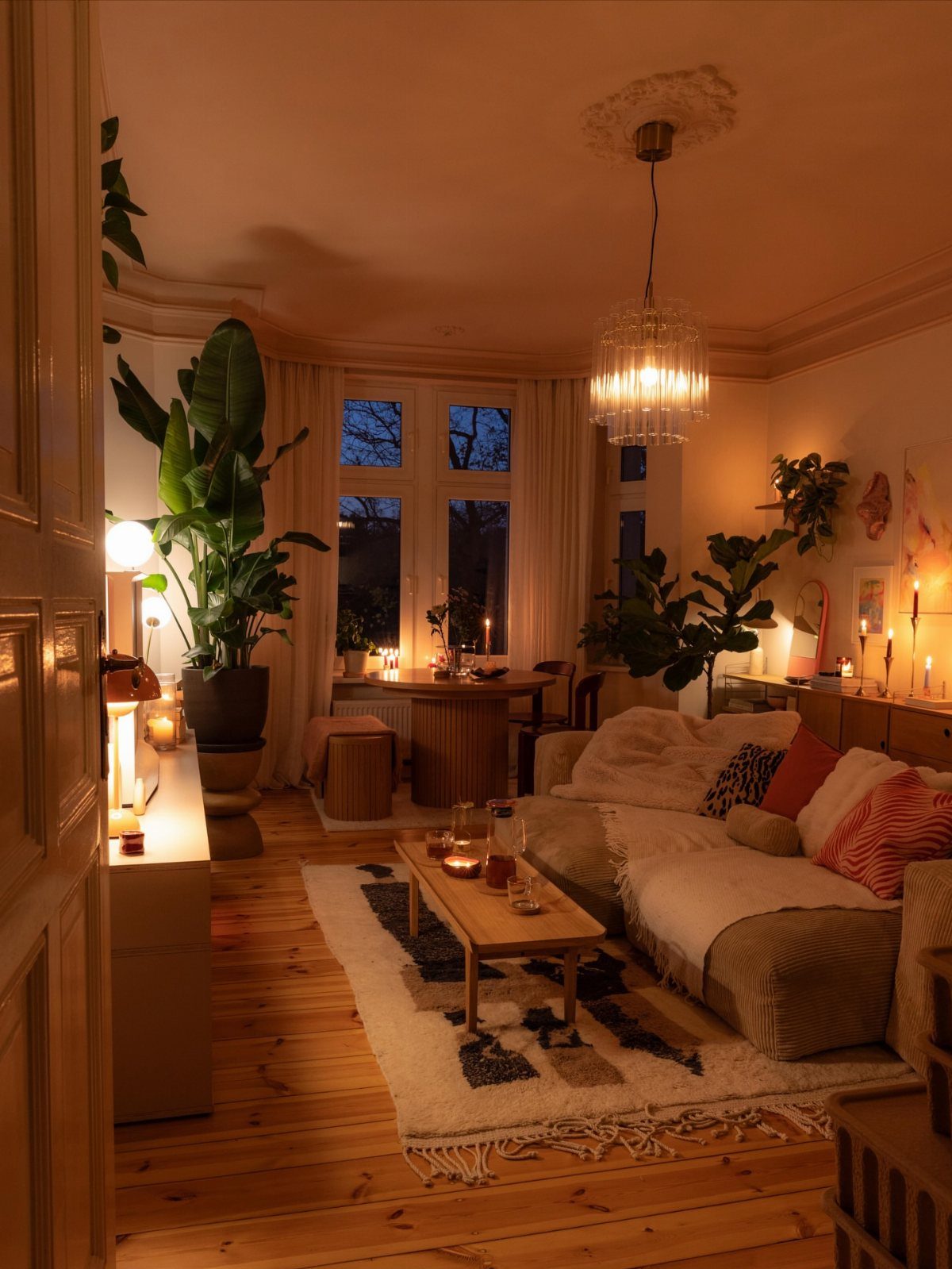Cozy living room illuminated by warm yellow lighting from a crystal chandelier.