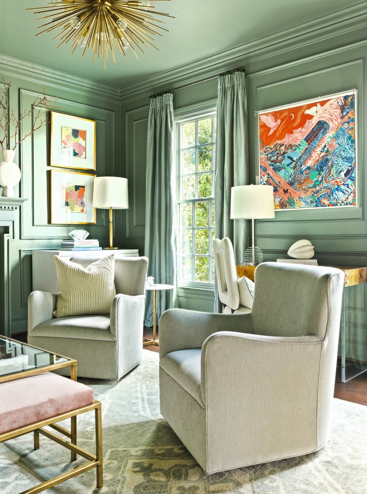 Sage green paneled room with grey armchairs and a gold starburst chandelier.