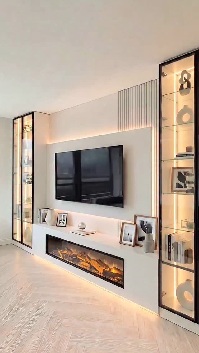 Two tall glass display cabinets flanking a white wall unit with a television.