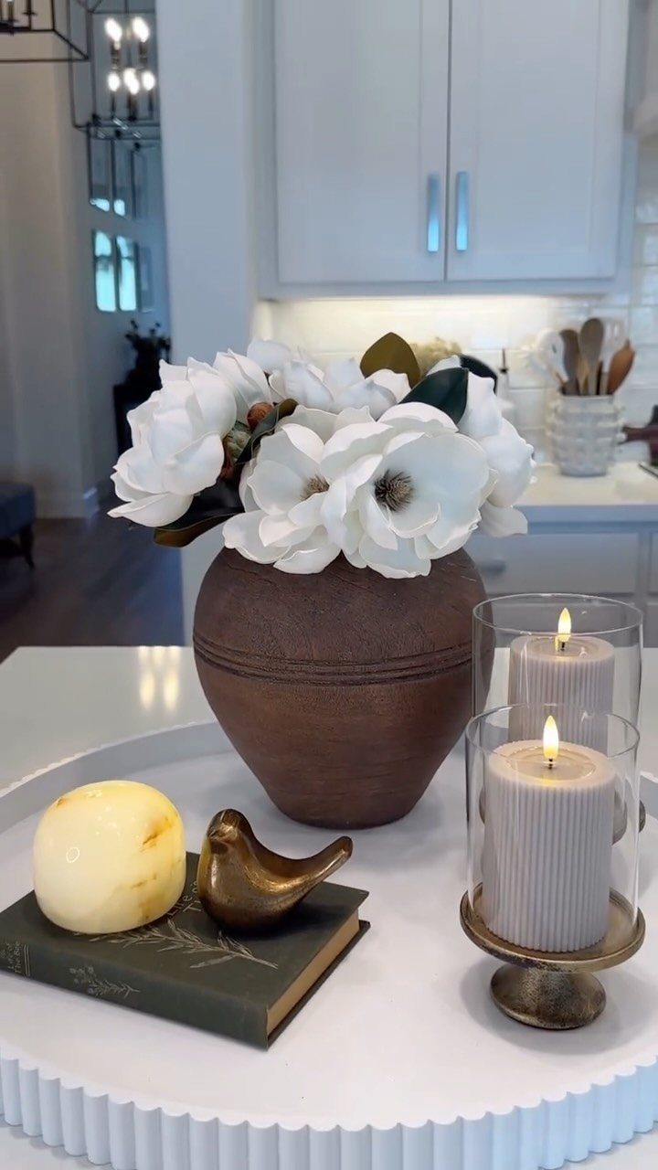 Brown ceramic vase with white magnolia flowers on a white decorative tray