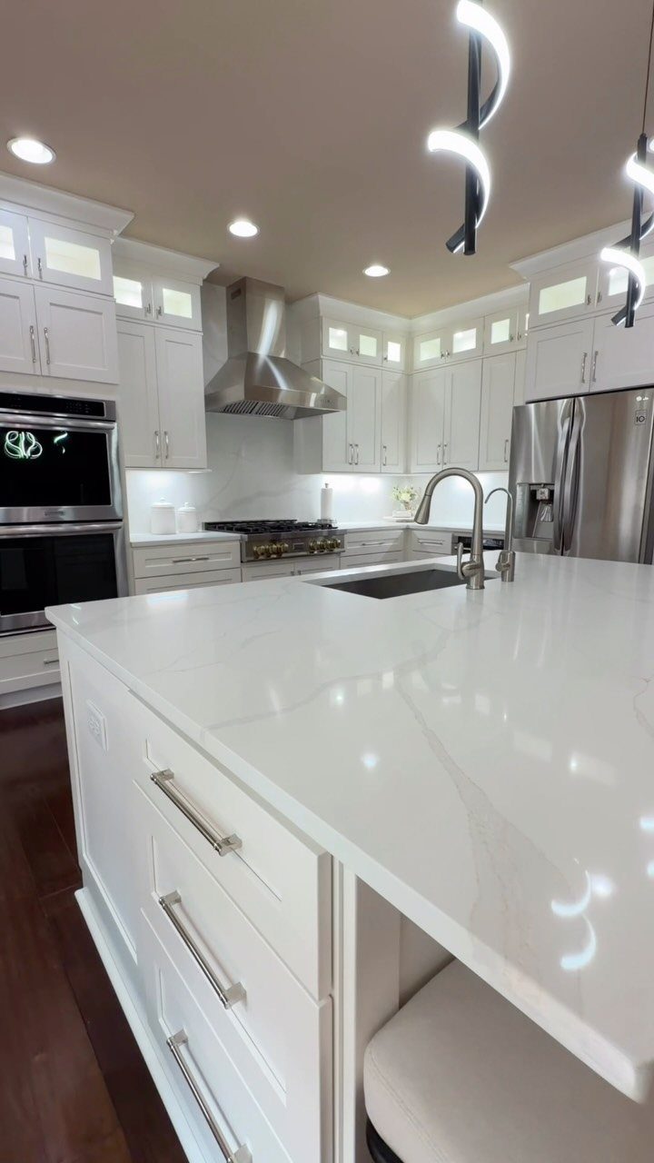 Modern white kitchen with curved LED pendant lights over a white quartz island